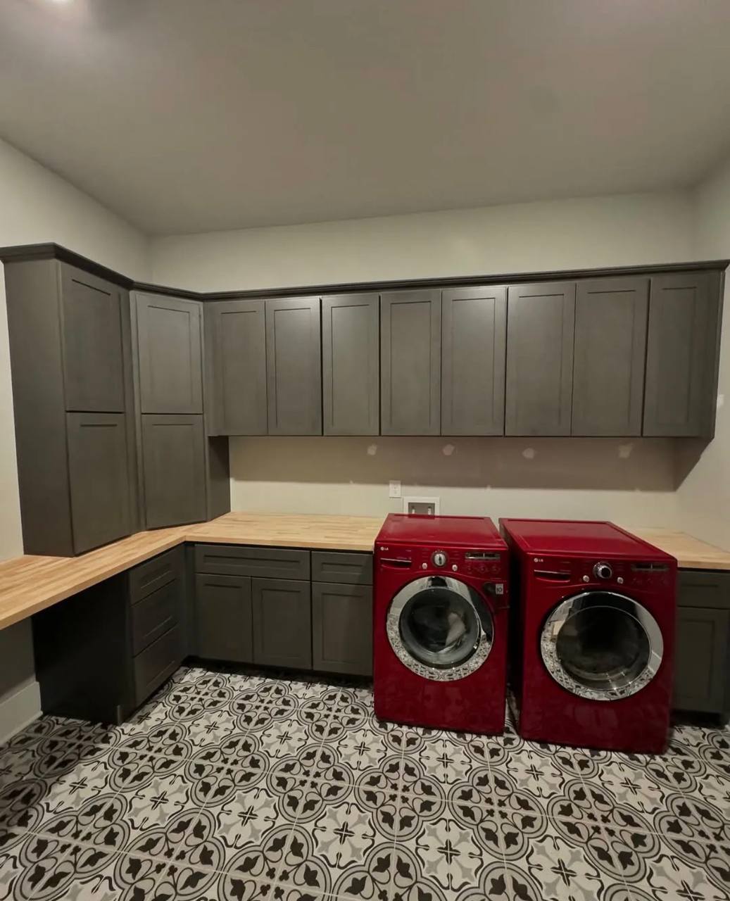 Storage cabinets, wood counters, and patterned tile in a laundry room.